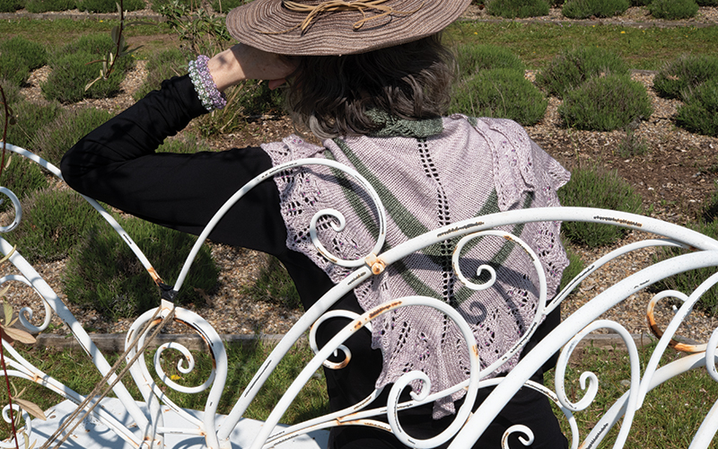 Sat on a garden seat wearing lavender yarn shawl